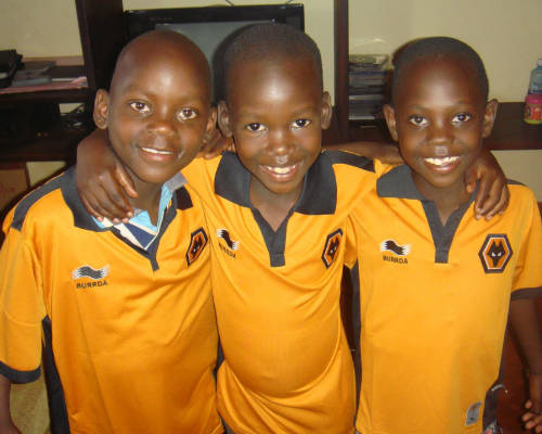 three young children smiling while wearing recycled clothing